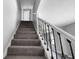 Gray carpeted staircase with black railing at 1472 N Grant Ave, Indianapolis, IN 46201