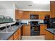 Modern kitchen with black appliances and wood cabinets at 6517 Emerald Hill Ct # Apt 312, Indianapolis, IN 46237