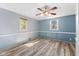 Bedroom with wood-look floors, light blue walls, and ceiling fan at 1912 N A St, Elwood, IN 46036