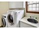 Well-equipped laundry room with white cabinets, utility sink, and modern appliances at 7178 Lockford N, Avon, IN 46123