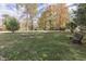 Spacious backyard with fire pit, bench, and mature trees in autumn colors at 6971 Lynx Dr, Nineveh, IN 46164