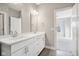 Bathroom with double vanity, white cabinets, and view to bedroom at 1817 N New Jersey St, Indianapolis, IN 46202