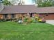 Charming brick ranch home with beautifully landscaped front yard, lush lawn, and colorful flowers at 6605 Donnelly Dr, Brownsburg, IN 46112