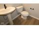 Half bathroom with pedestal sink, toilet, and wood-look flooring at 16990 Silo Ridge Way, Noblesville, IN 46060