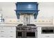 Modern kitchen with stainless steel range, blue hood, and white cabinets at 2505 Riverside Dr, Columbus, IN 47201