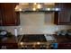 Stainless steel gas cooktop and range hood in a kitchen with dark wood cabinets at 7610 Monte Carlo Way, Indianapolis, IN 46278