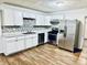 Renovated kitchen with white cabinets, stainless steel appliances, and mosaic backsplash at 2442 N Franklin Rd, Indianapolis, IN 46219