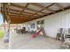 Long covered patio with wooden ceiling beams, table, chairs, and a slide at 26735 Six Points Rd, Sheridan, IN 46069