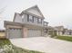Two-story house with gray siding, brick accents, and a three-car garage; view of neighboring houses at 259 Lar Lan Dr, Danville, IN 46122