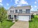 Two-story home with gray and blue siding, a white garage door, and a landscaped front yard at 1285 Greenwood Station Blvd, Greenwood, IN 46143