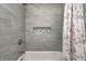 Grey tiled bathtub and shower with a decorative niche and floral shower curtain at 5909 Buttonwood Dr, Noblesville, IN 46062