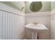 Charming powder room features a pedestal sink, beadboard wainscoting, and an elegant round mirror at 7290 Lockford Walk N, Avon, IN 46123