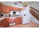 Kitchen with wood cabinets, white appliances, and view of living room at 1127 Grant Cir, Cicero, IN 46034