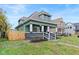 Renovated green house with gray accents, a wooden fence, and a landscaped yard at 1542 S Alabama St, Indianapolis, IN 46225