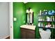 Green bathroom with single vanity, toilet, and storage shelves at 7922 S Sherman Dr, Indianapolis, IN 46237