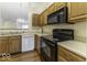 Galley kitchen with oak cabinets, black appliances, and double sink at 8520 Bison Woods Ct, Indianapolis, IN 46227