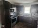 Modern kitchen featuring dark cabinetry, granite countertops, and stainless steel appliances at 306 E Cherry St, Advance, IN 46102