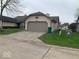 Beige one car garage with driveway and grassy yard at 4112 Eagle Cove E Dr, Indianapolis, IN 46254