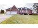 Brick house with a three-car garage and landscaped lawn at 9699 Prairiewood Way, Carmel, IN 46032