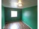 Green-walled bedroom with hardwood floors and a window at 504 E Park St, Trafalgar, IN 46181