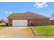 Brick two-car garage with white door and landscaped yard at 5059 Countess Dr, Columbus, IN 47203