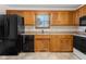 Kitchen featuring oak cabinets, black appliances, and tile flooring at 5059 Countess Dr, Columbus, IN 47203