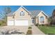 Beige two-story house with three-car garage and landscaped yard at 4770 Winterberry Pl, Columbus, IN 47201