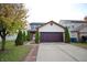 Two-story house with a brown door and attached garage. Lush green landscaping surrounds the property at 7144 Kimble Dr, Indianapolis, IN 46217