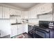 Bright kitchen with white cabinets, black appliances, and dark wood-look floors at 1003 Avalon Ln, Anderson, IN 46017