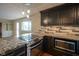 Modern kitchen with granite countertops, dark cabinets, and stainless steel appliances at 5837 Baron Ct, Indianapolis, IN 46250