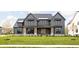 Two-story farmhouse with gray siding, stone accents, and a welcoming front porch at 5187 Abington Way, Zionsville, IN 46077