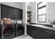 Modern laundry room with dark cabinetry, LG washer and dryer, and herringbone flooring at 5187 Abington Way, Zionsville, IN 46077