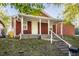 Renovated red bungalow features a covered porch and steps leading to the front door at 1467 S Illinois St, Indianapolis, IN 46225