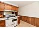 Retro kitchen features wood cabinets, a white stove and wood paneled walls at 1500 S Anderson St, Elwood, IN 46036