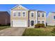 Two-story house with tan siding, a white garage door, and landscaping at 10808 Inspiration Dr, Indianapolis, IN 46259