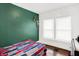 bedroom with green accent wall, hardwood floors, and window at 527 N Hamilton Ave, Indianapolis, IN 46201