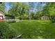 Large, grassy backyard with a storage shed and white picket fence at 10757 Kelly Ct, Indianapolis, IN 46231