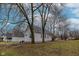 Side exterior view of a gray, single-story home surrounded by bare trees and grass at 2709 Station St, Indianapolis, IN 46218