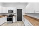 White kitchen with stainless steel appliances, wood countertops, and ample cabinet space at 2709 Station St, Indianapolis, IN 46218