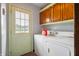 Laundry room with washer, dryer, wooden cabinets, and a door leading outside at 4832 E 200 N, Anderson, IN 46012