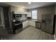 Compact kitchen with white cabinets, stainless steel appliances, and gray wood-look flooring at 416 N Mulberry St, Muncie, IN 47305