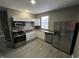 Compact kitchen with white cabinets, stainless steel appliances, and gray wood-look flooring at 416 N Mulberry St, Muncie, IN 47305