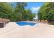 In-ground pool with surrounding patio, landscaping, and an American flag at 7701 Center Lake Rd, Nineveh, IN 46164