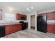 Modern kitchen with dark wood cabinets, black appliances, and vinyl flooring at 4086 Lassen Ln, Indianapolis, IN 46235