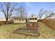 Backyard view of yellow home with attached garage, enclosed porch, and garden beds at 6440 Maple St, Indianapolis, IN 46236