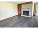 Living room with gray wood-look flooring, a brick fireplace with built-in shelves, and light yellow walls at 117 N Elma St, Anderson, IN 46012