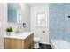 Modern bathroom featuring blue tile, patterned wallpaper, and a wood vanity at 5615 Brouse Ave, Indianapolis, IN 46220