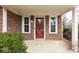 Close-up of the home's front porch and red entry door, framed by brick and shrubbery at 5810 Spring Oaks Way, Indianapolis, IN 46237