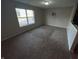Empty living room with neutral gray walls, carpeted flooring, and a large window at 6215 E 11Th St, Indianapolis, IN 46219
