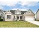 Beige two-story house with a white garage door and landscaping at 11463 Long Sotton Ln, Fishers, IN 46037